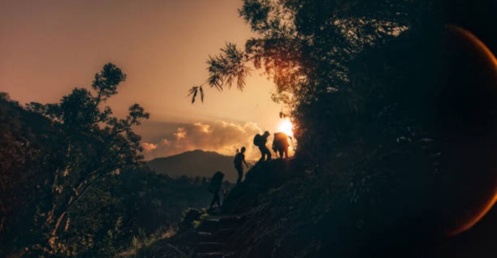 Travel blogger capturing a panoramic mountain and forest view at sunset.