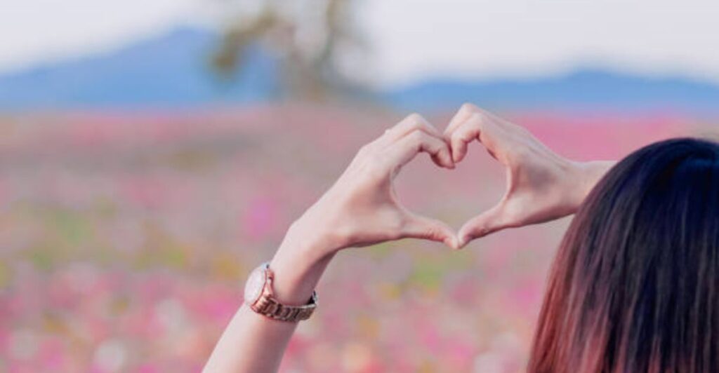 Hands giving a thoughtful handwritten thank-you note with flowers beside it.