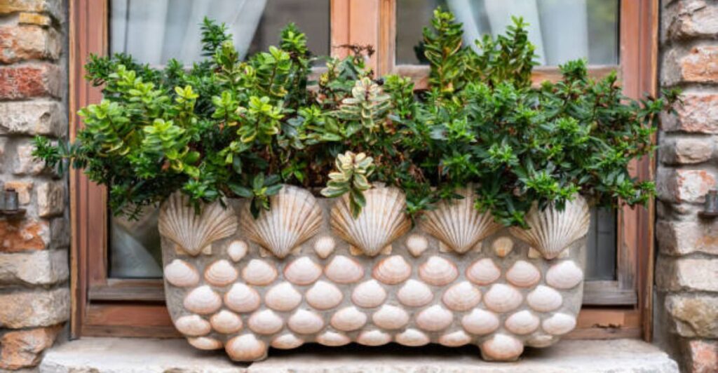 Decorative glass jar filled with seashells, sand, and fairy lights for summer décor styling.