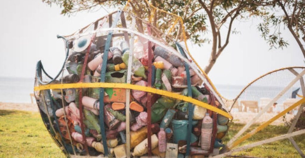 Children creating colorful summer crafts using recycled cardboard, bottles, and paper rolls on a sunny table.