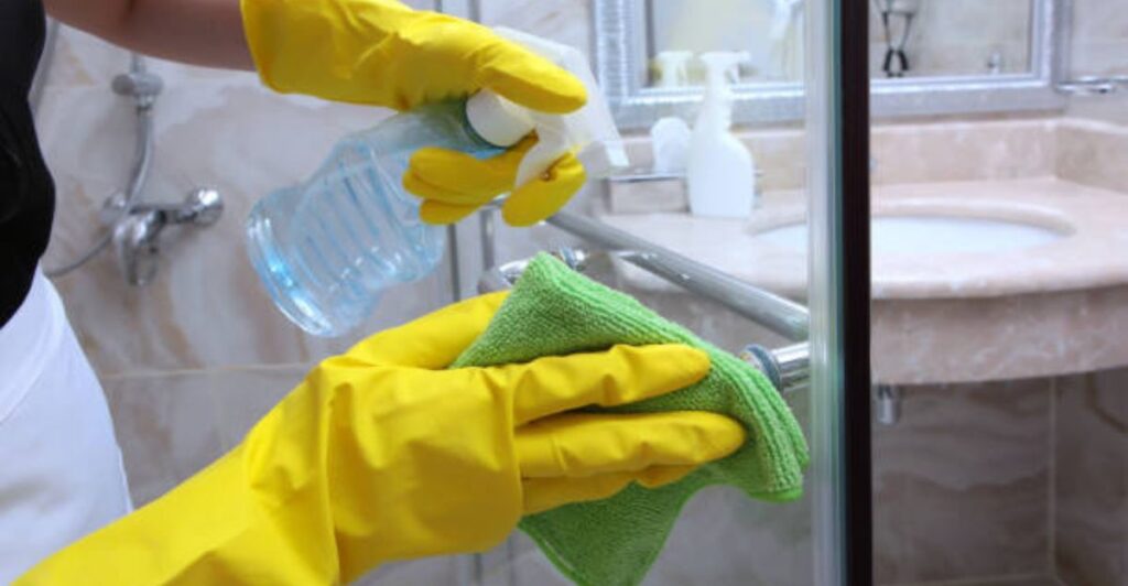 Busy homeowner using a squeegee to clean large glass doors quickly and efficiently.