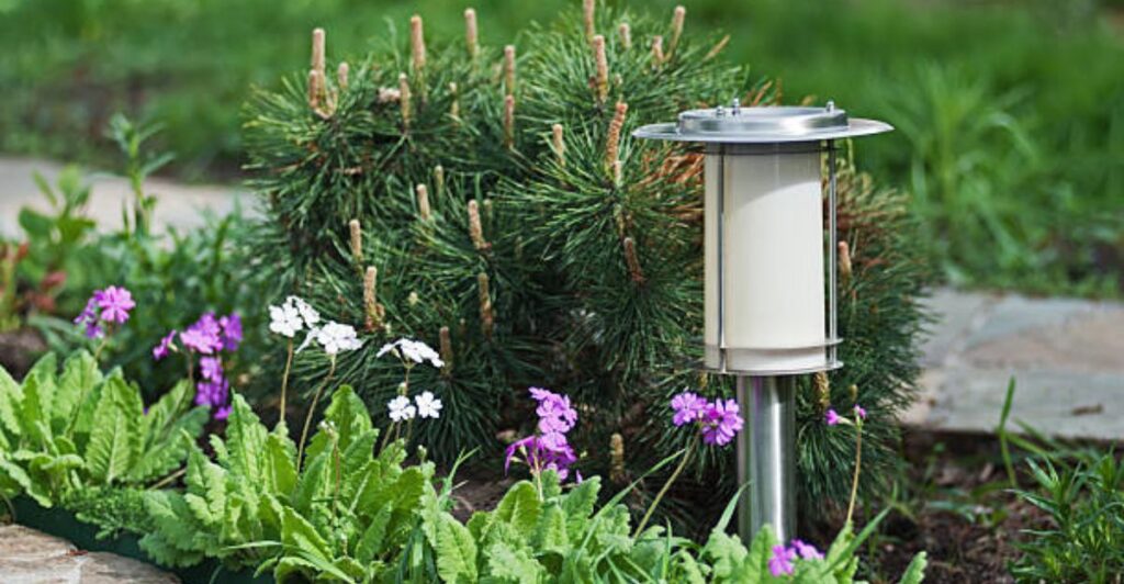Decorative solar lanterns placed along a garden path with natural stone edging and vibrant seasonal blooms.