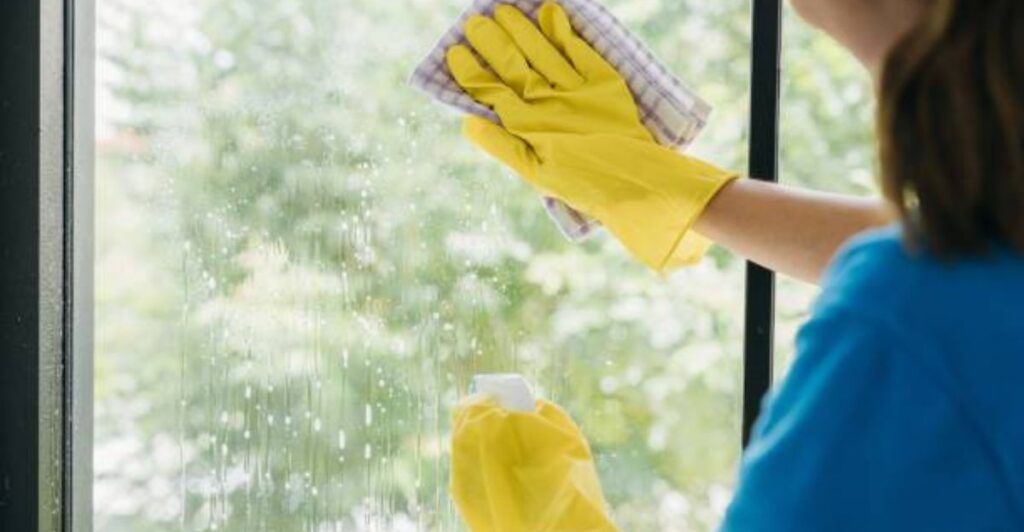 Sparkling glass window being cleaned with a microfiber cloth in a bright modern living room.