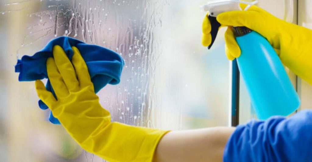 Busy homeowner using a squeegee to clean large glass doors quickly and efficiently.