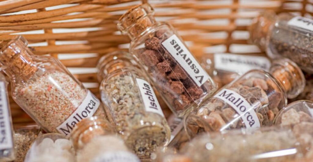 Glass bottle filled with layered beach sand and small coastal treasures.