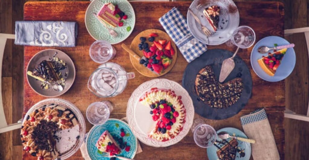 Fresh strawberry layer cake topped with whipped cream, sliced strawberries, and mint leaves on a cake stand.