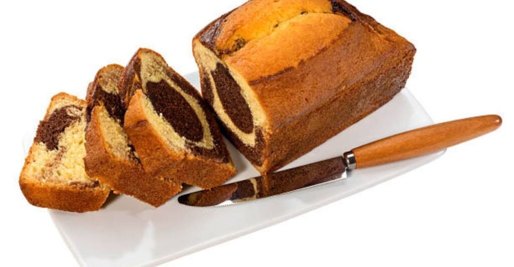 Classic marble cake with swirls of vanilla and chocolate topped with smooth chocolate glaze on a serving plate.