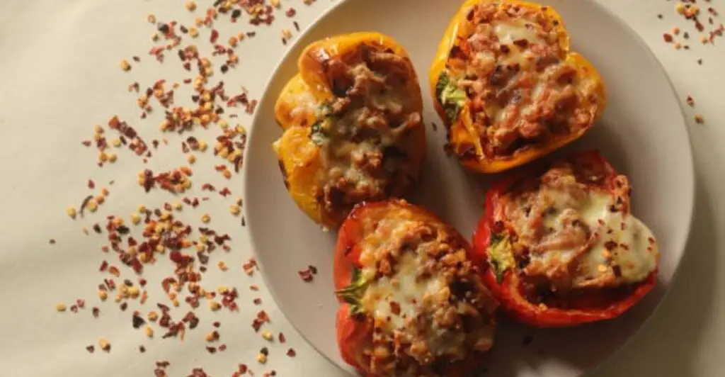 Golden baked sweet potatoes sliced open and topped with fresh parsley on a wooden table.