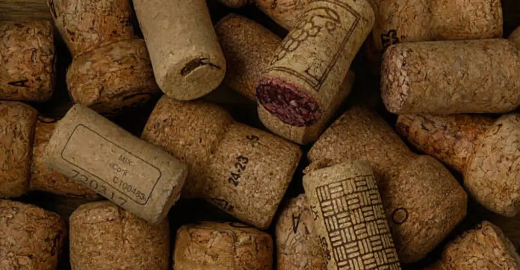 Handmade wine cork bulletin board mounted on a wall with colorful notes and photos.