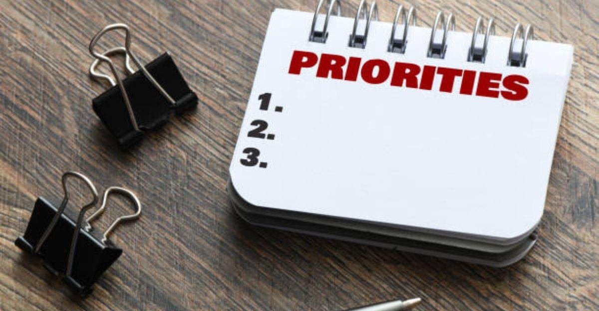 Person writing three important daily priorities in a planner to stay focused and productive.