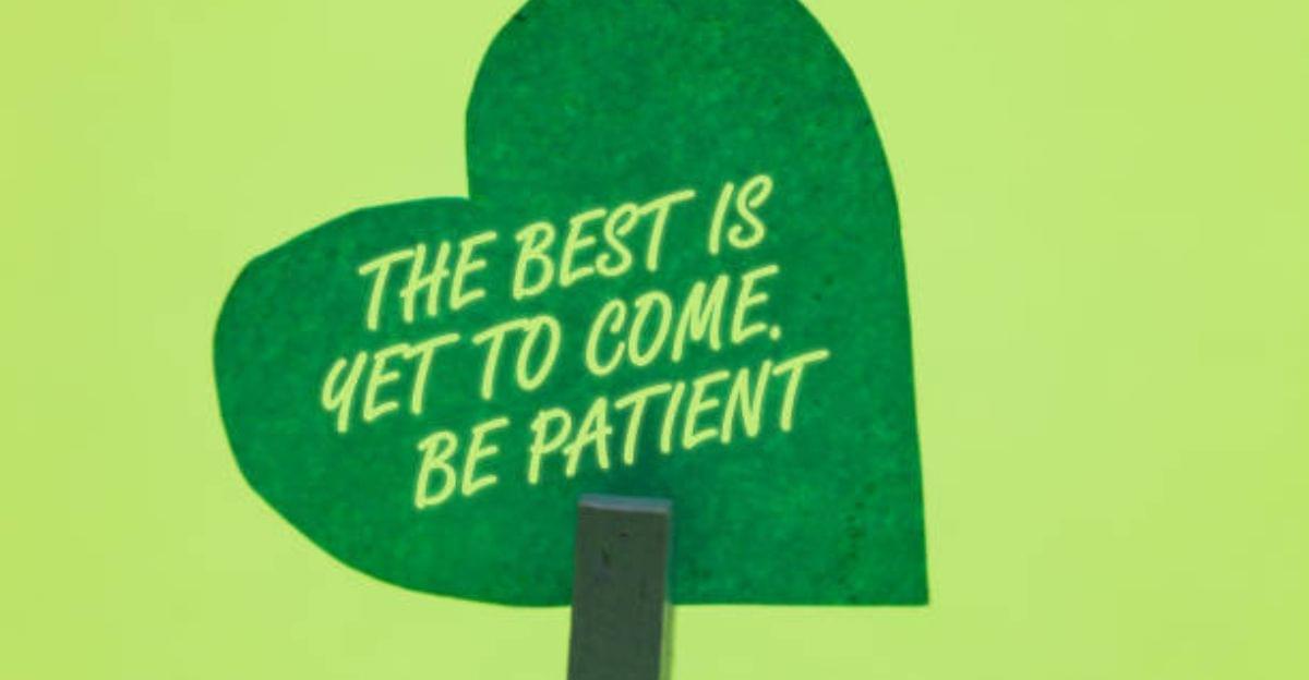 Heart-shaped wooden decoration beside blooming flowers representing patient love and lasting relationships.