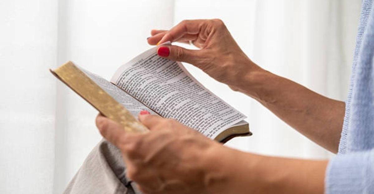 Hands folded in prayer over an open Bible with a wooden cross symbolizing faith and devotion.
